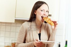 8988341-happy-woman-biting-in-a-croissant-in-a-kitchen1